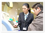 玄関を入ると先ず目に入る総合案内と再診受付機の前で受付・エスコート業務を行う。イメージ